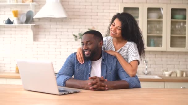 Feliz pareja multirracial usando un portátil en casa — Vídeo de stock