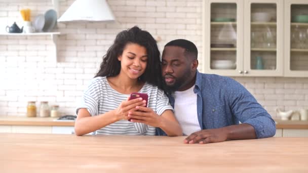 Pareja multirracial feliz usando un smartphone en casa — Vídeos de Stock