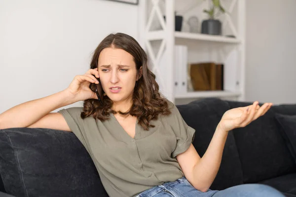Annoyed woman talks over phone at home