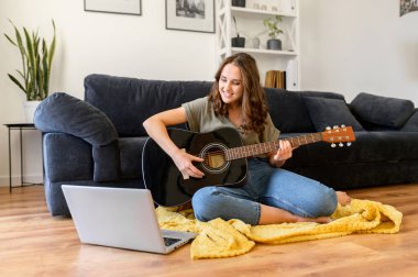 Çekici kıvırcık kadın evde gitar çalıyor.
