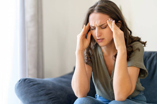 Attractive curly young woman suffering from headache
