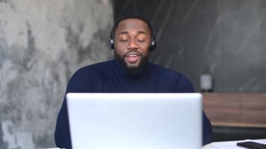 Siyah iş adamı dizüstü bilgisayarında video konferansı yapıyor. Evde oturuyor.