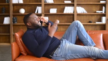Afro-Amerikalı bir adamın telefon konuşması kanepede yatar.
