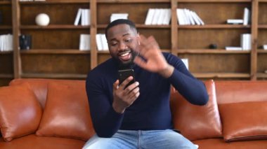 Video görüşmesi için akıllı telefon kullanan Afrikalı adam.