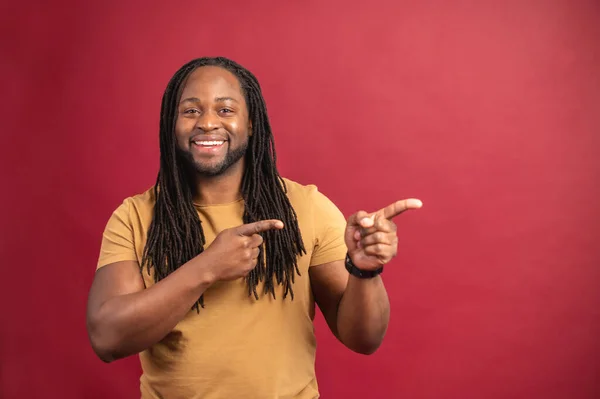 Positiv svart man ser ut och pekar åt sidan med båda pekfingrarna — Stockfoto