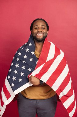 Amerikan bayrağıyla kaplanmış gülümseyen siyah kaslı adam.