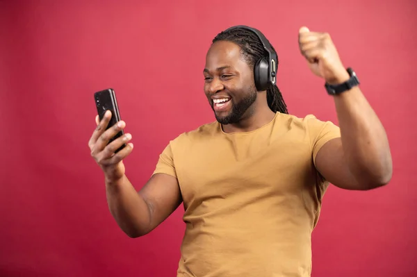 Isolerad ung afrikansk man lyssnar på musik med hörlurar — Stockfoto
