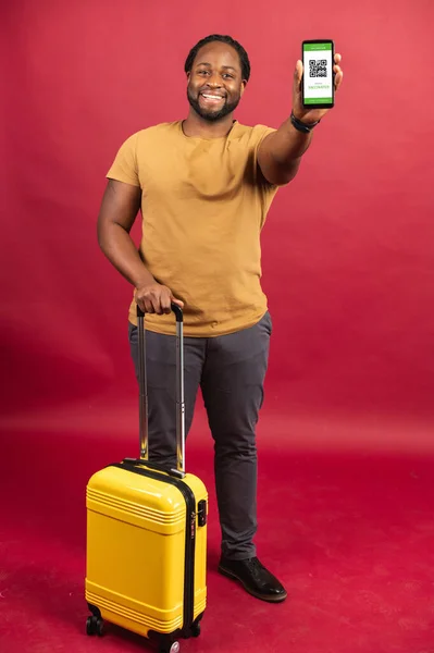 Glad afrikansk man stående med handväska och mobiltelefon i händerna — Stockfoto