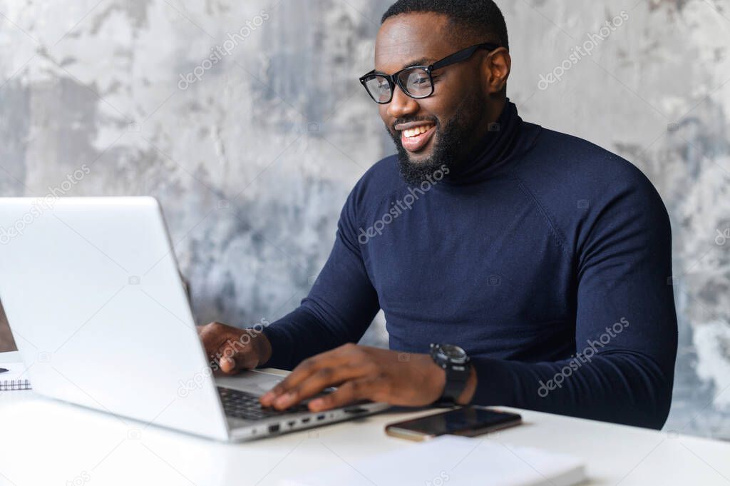 Confident African-American man using a laptop at office