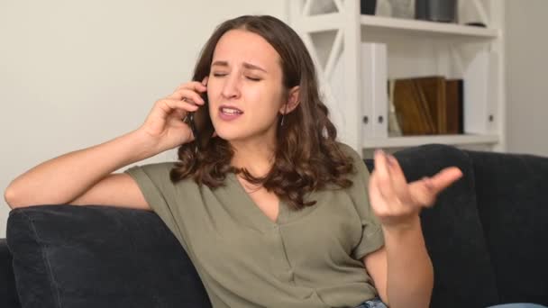 Irriterad kvinna talar via smartphone hemma — Stockvideo