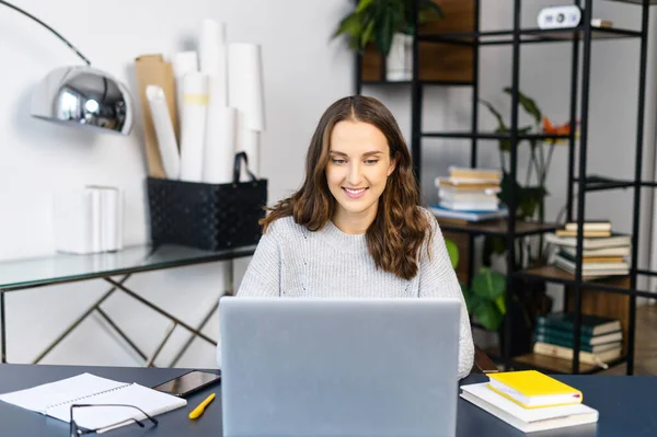 Alegre empleado femenino trabaja con un ordenador portátil en la oficina moderna —  Fotos de Stock