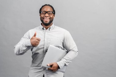 Akıllı Afro-Amerikalı adam, gri üzerine izole edilmiş bir laptop kullanıyor.