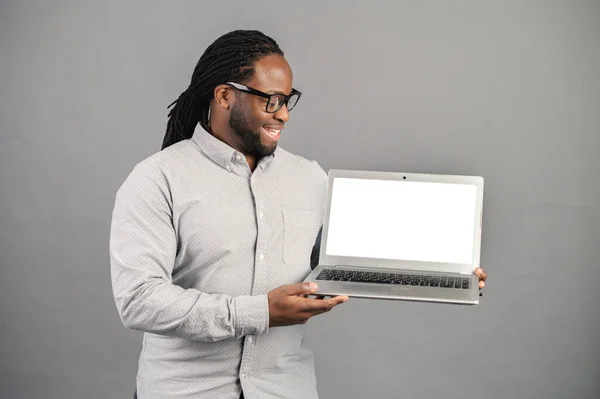 Leende afroamerikansk man med laptop isolerad på grå — Stockfoto