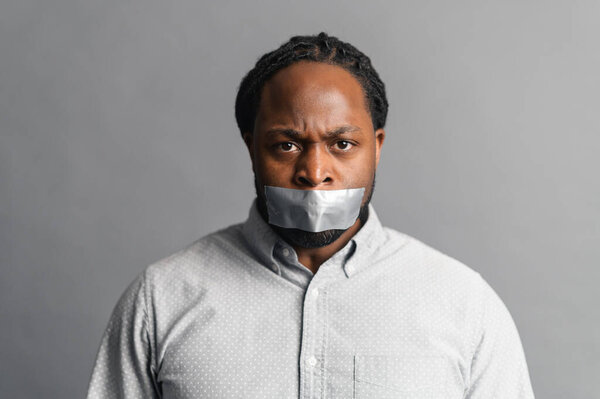 African-American man with a sealed mouth, isolated on grey
