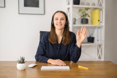 Gülümseyen kadın ofiste kulaklık takıyor.