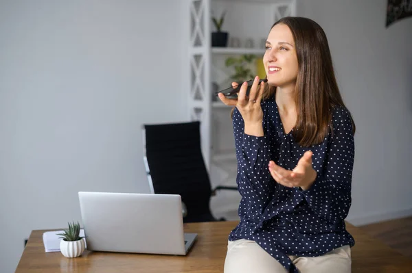 Junge Frau nimmt Sprachnachricht im Büro auf — Stockfoto