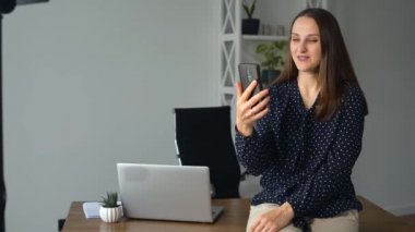 Modern genç iş kadını video görüşmesi için akıllı telefon kullanıyor.,