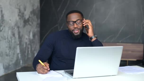 Positivo afroamericano freelancer masculino tiene conversación telefónica — Vídeos de Stock