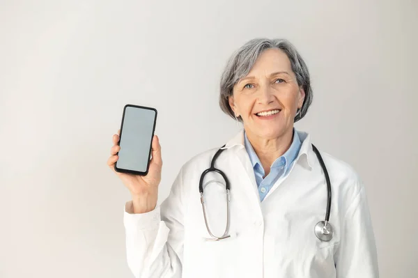 Medico anziano donna in piedi con uno smartphone — Foto Stock