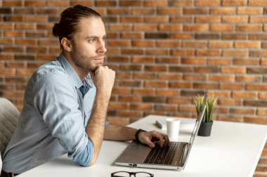 Gündelik kıyafet giyen bir adam dizüstü bilgisayar kullanıyor.