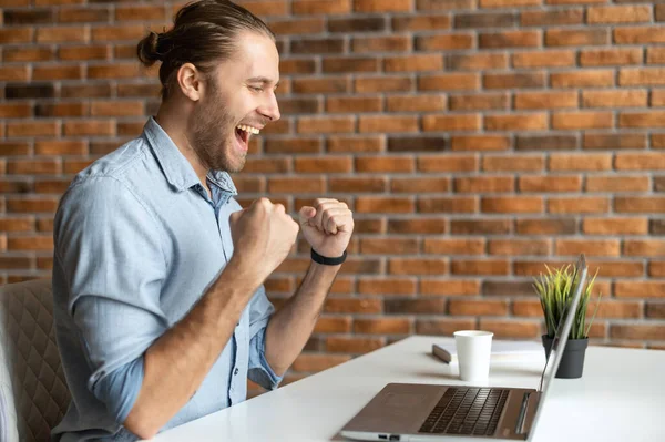 Entusiastiska affärsman håller händerna i knytnävarna, en glad frilansare skriker ja med triumf — Stockfoto