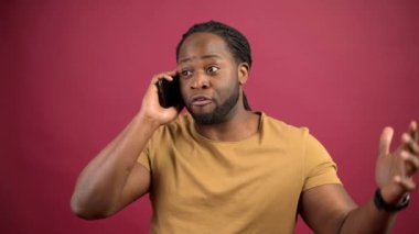 Sıradan tişörtler giyen Afro-Amerikalı adam akıllı telefondan konuşuyor.