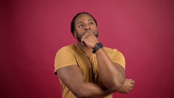 Verwirrter Afroamerikaner in gelbem T-Shirt isoliert auf rotem Grund — Stockvideo
