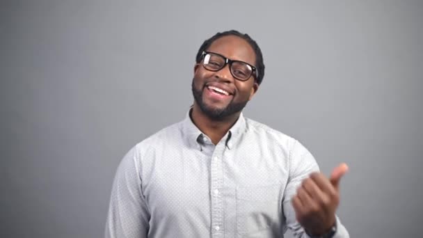 Cheerful African-American man looks at the camera and gesturing: come here — Stock Video