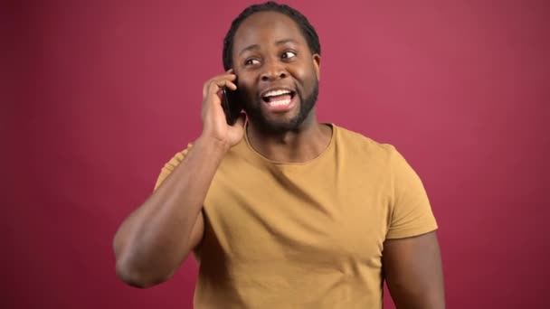 Αφρο-Αμερικανός τύπος που φοράει casual t-shirt και μιλάει στο smartphone — Αρχείο Βίντεο