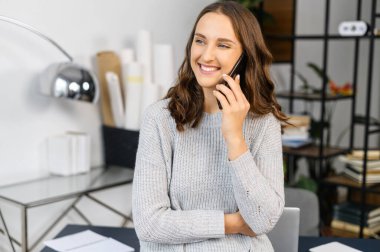 Gülümseyen kadın telefonla konuşur ve kameraya bakar.