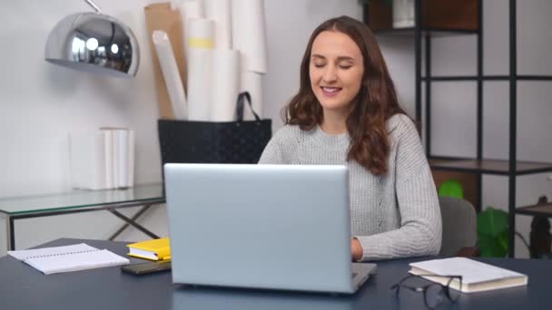 Vrolijke jonge vrouw heeft videogesprek op de laptop op kantoor — Stockvideo
