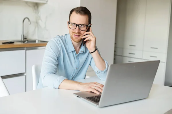 Inteligente jovem empresário fala ao telefone usando laptop — Fotografia de Stock