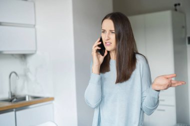 Sinirli genç kadın akıllı telefondan konuşuyor.