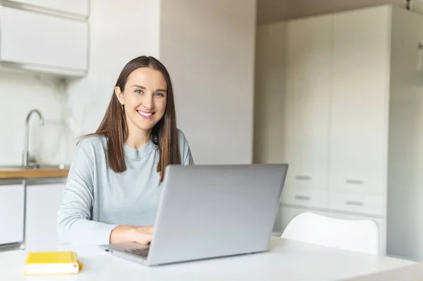 Charmante junge Frau nutzt Laptop für die Arbeit von zu Hause aus, — Stockfoto