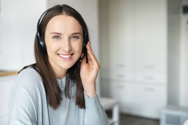 Mujer joven positiva con auriculares habla en línea — Foto de Stock