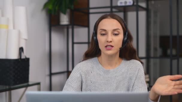 Woman wearing wireless headset using a laptop computer for communication — Stock Video