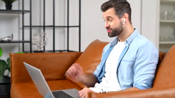 En fokuserad man bär casual shirt med hjälp av en bärbar dator för videosamtal — Stockvideo