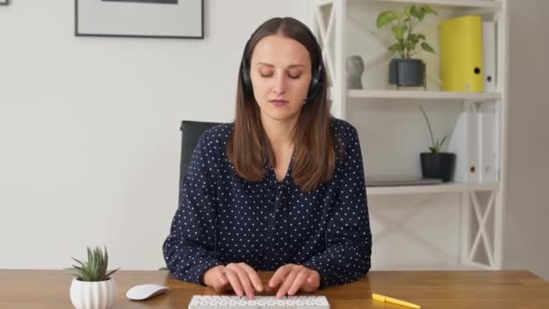 Moderne Geschäftsfrau mit Headset tippt und blickt in die Kamera — Stockvideo