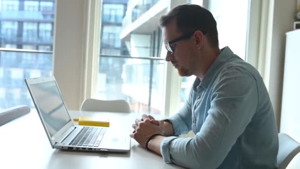 Travailleur masculin confiant assis au bureau avec un ordinateur portable et travaillant à distance — Video