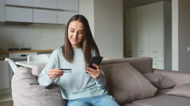 İnternetten alışveriş yapmak için akıllı telefon ve kredi kartı kullanan bir kadın.