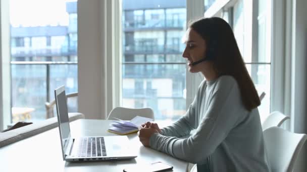 Wanita muda memakai headset menggunakan laptop untuk panggilan video — Stok Video