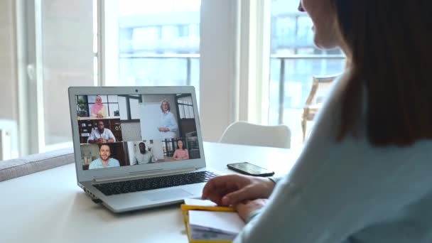 Ung kvinde ved hjælp af bærbar computer til videomøde med gruppe af forskellige mennesker – Stock-video