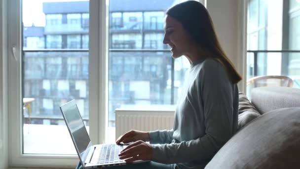 Glückliche junge Frau nutzt Laptop für Videoverbindung von zu Hause aus — Stockvideo