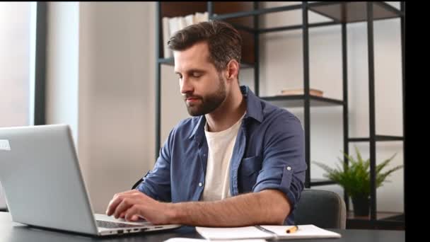 Guapo barbudo empresario masculino en ropa casual utilizando el ordenador portátil para el trabajo remoto — Vídeos de Stock