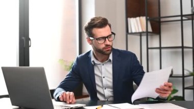 Resmi takım elbiseli sinirli genç işadamı bir kağıt parçasını buruşturup atıyor.