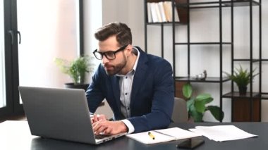 Resmi takım elbiseli zeki ve hırslı bir iş adamı dizüstü bilgisayarla çalışıyor.