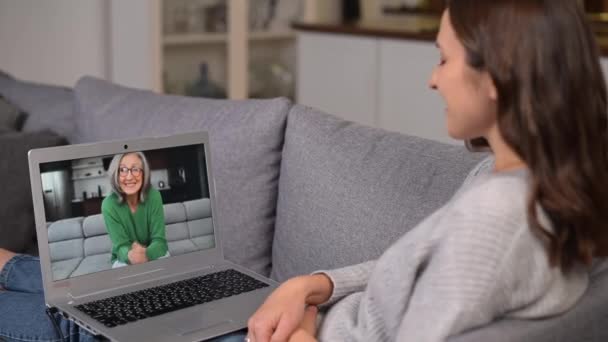 Joven alegre usando un ordenador portátil para la conexión de vídeo con una mujer de edad avanzada — Vídeos de Stock
