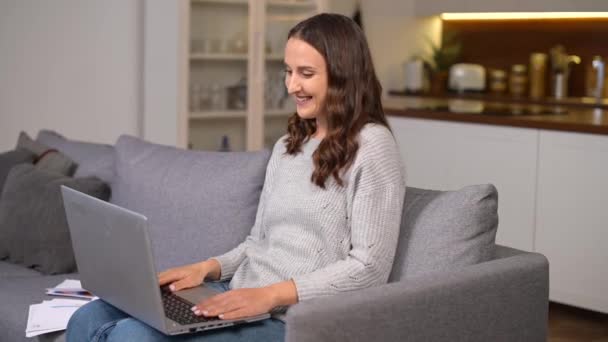 Fröhliche junge Frau hat Videotreffen auf der Couch zu Hause — Stockvideo