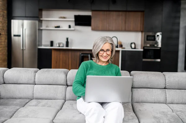 Пожилая женщина пользуется ноутбуком дома — стоковое фото