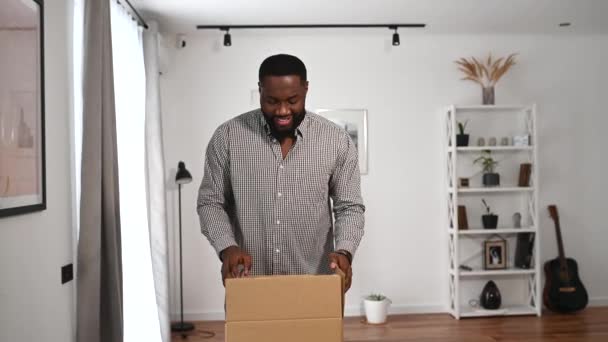En afrikansk kille packar upp en paketlåda — Stockvideo